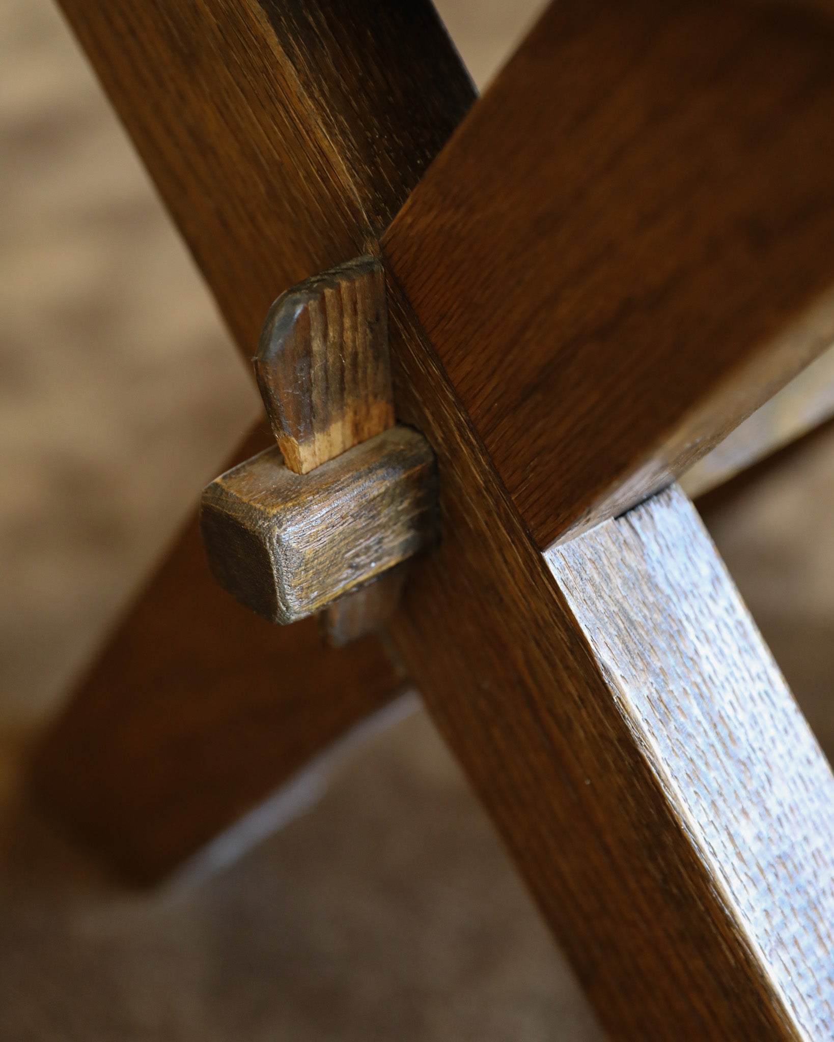 Close-up detail of a wooden chair or table leg joint, showing a dark brown wood grain with a lighter natural wood dowel.