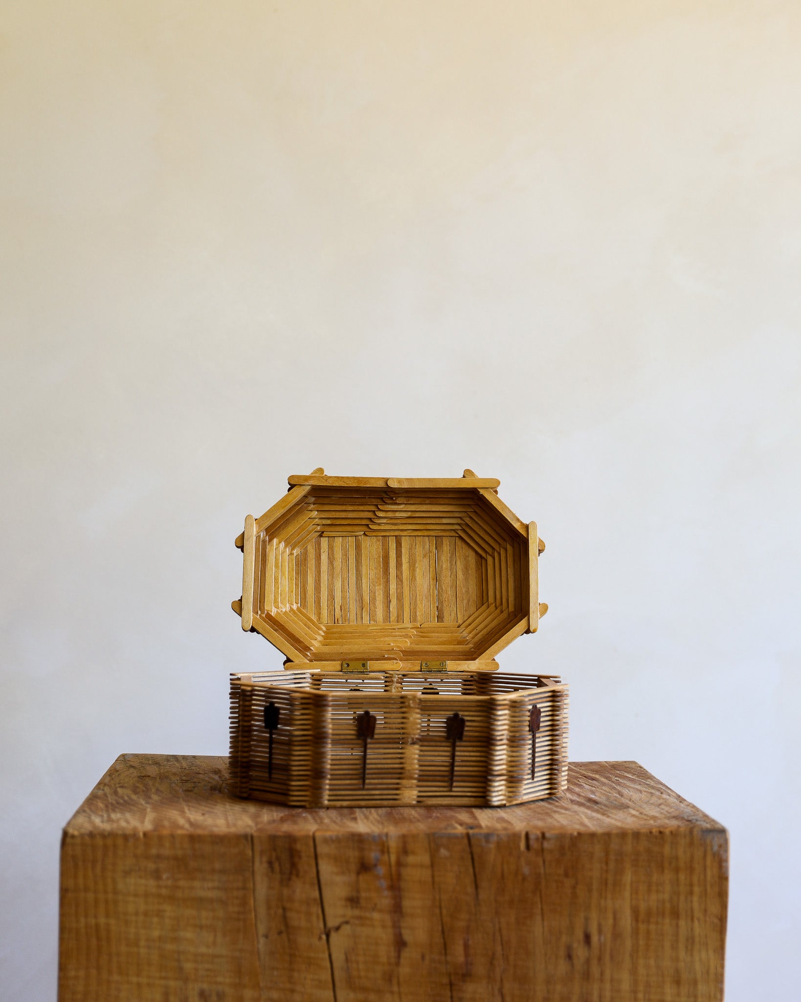 and open tramp art box made of popsicle sticks on a wooden stump with a cream background