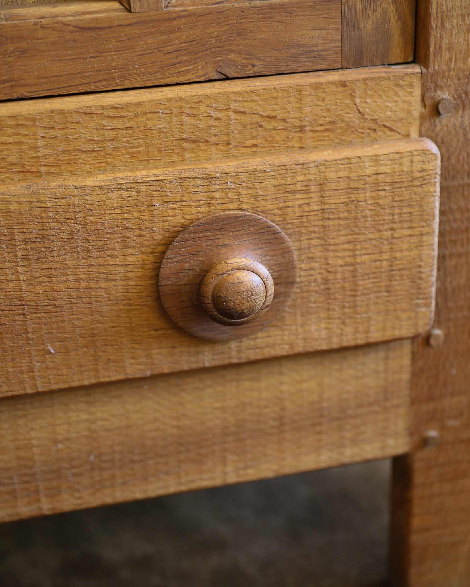 Close-up of a warm medium-brown wooden drawer with a round wooden knob, showing the wood grain texture and finish.