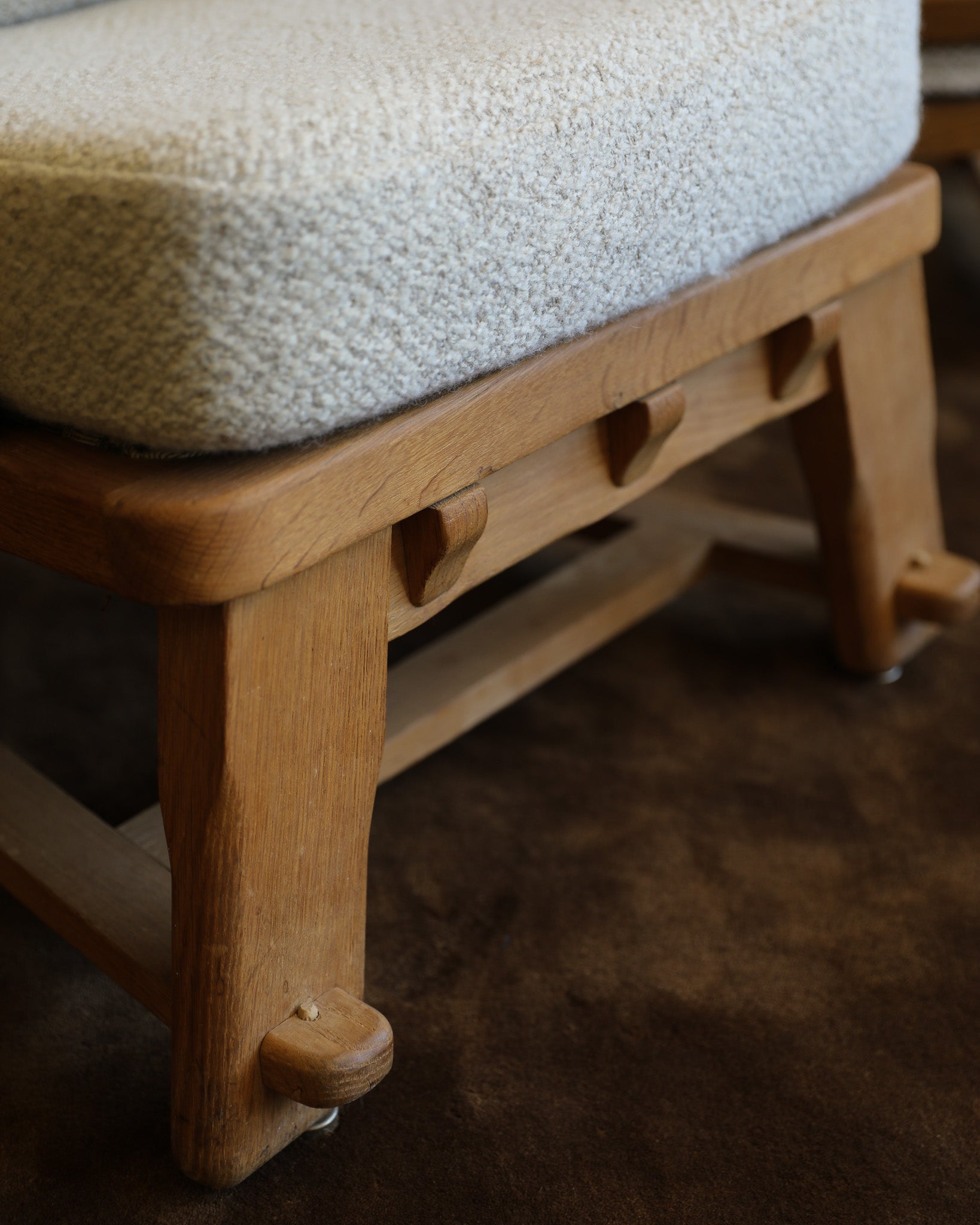 Two wooden chairs with tufted bouclé cushions in a neutral indoor setting with a brown rug and plain wall.
