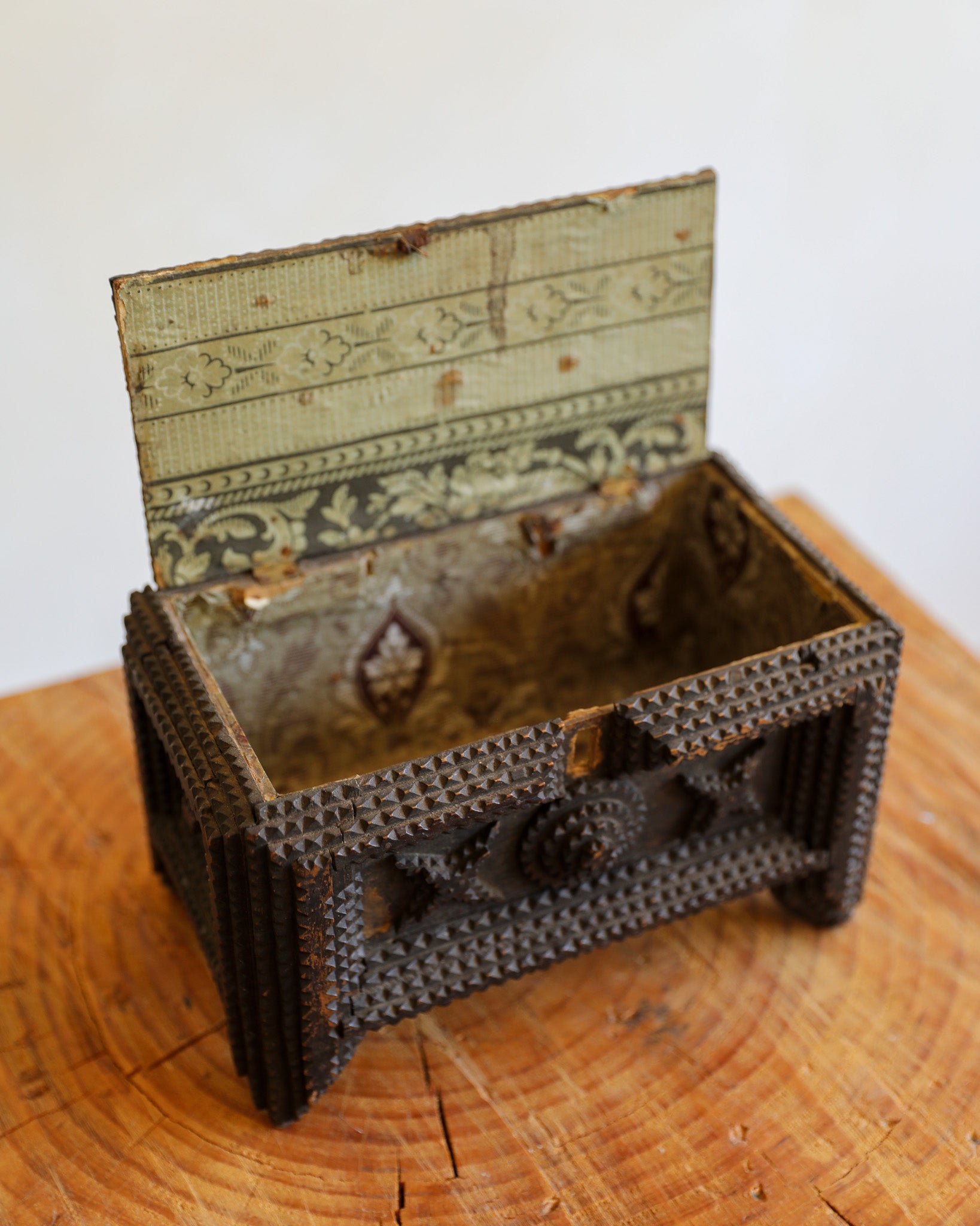 open tramp art box with antique paper lining on wood stump with cream background